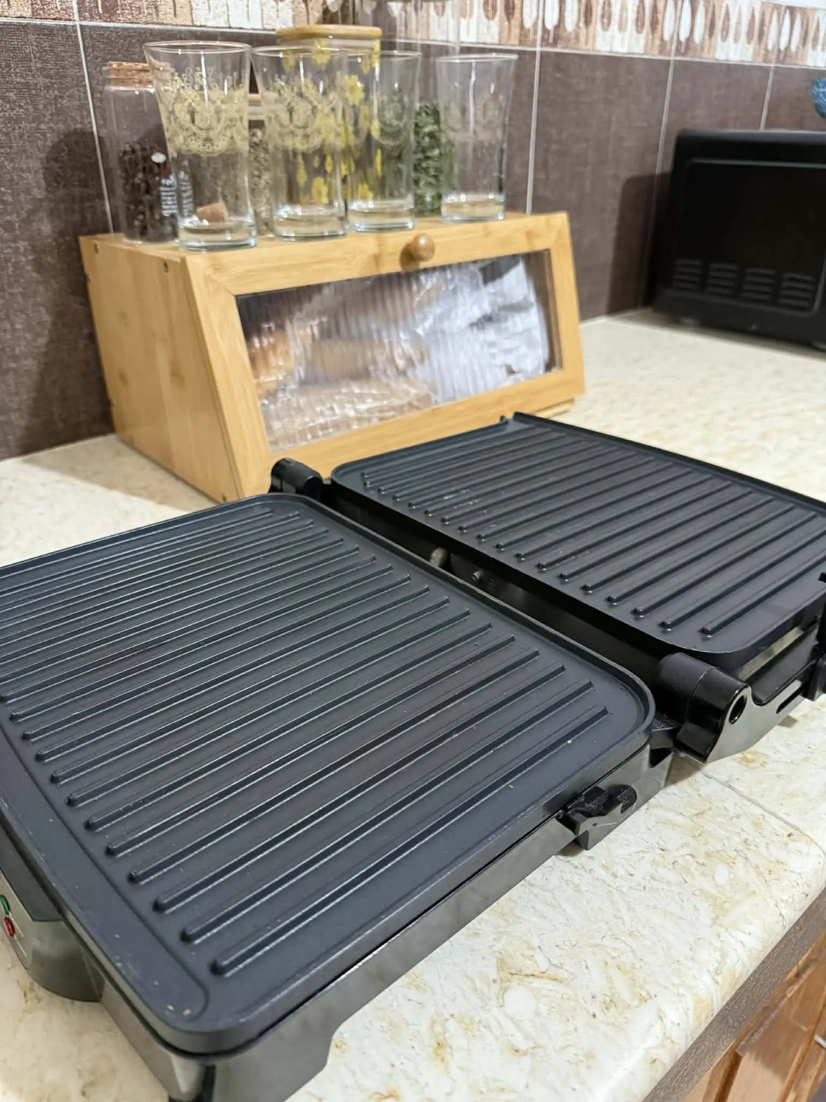 Grille électrique 2000 watt noire avec surface de cuisson antiadhésive nervurée et design compact pliable