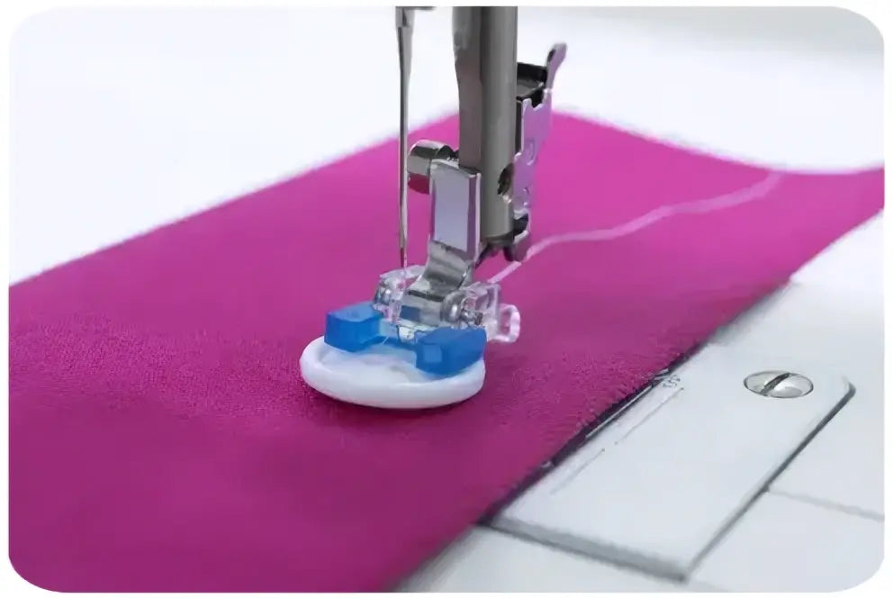 Machine a coudre 1340-v avec pied presseur en plastique bleu et transparent sur base blanche cousant un tissu rose vif
