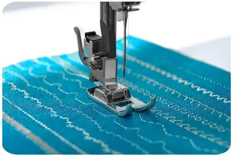 Machine a coudre 1740-v pied presseur argent en metal sur tissu turquoise avec couture blanche en zigzag
