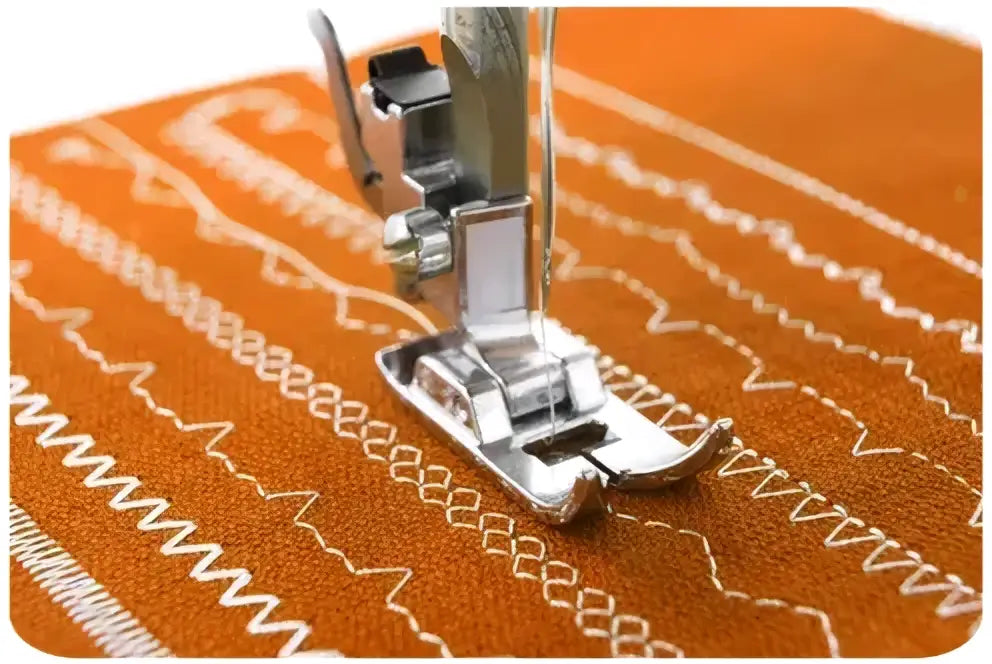 Pied presseur argenté pour machine à coudre 1930-v sur tissu orange avec surpiqûres blanches en zigzag
