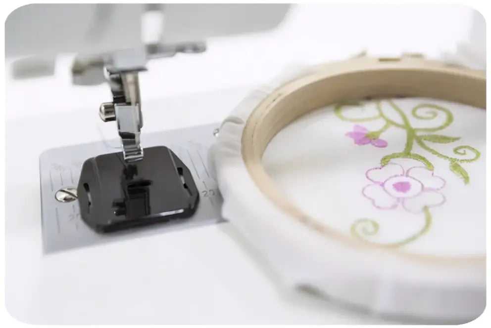 Machine a coudre 2321-V avec tambour a broder blanc tenant un tissu a motif floral rose et vert