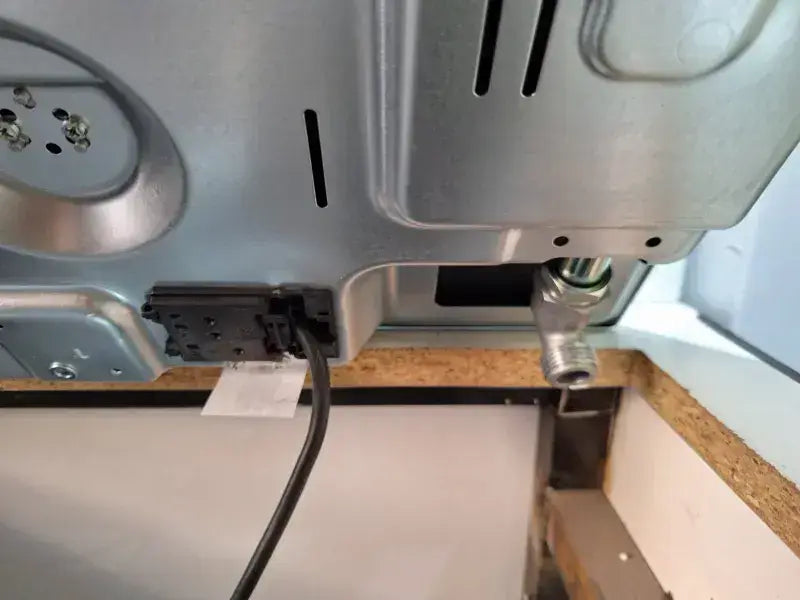 Vue arrière de la table de cuisson 4f céramique avec panneau métallique argenté, câble d’alimentation noir et raccord métallique