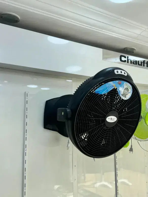 Ventilateur de sol noir avec grille circulaire et trois boutons de contrôle sur le dessus du boîtier mural